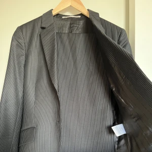 Kostym från Tiger of Sweden - Kritstrecksrandig kostym i ull/viskos strl 42 (byxor passar 40-42, kavaj passar 38-42)  Aldrig använd av mig, men second hand  Knappt märkbara fläckar på kavajens framsida 