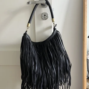 Väska med fransar  - Säljer denna väska med fransar från hm, den är i bra skick förutom att den är lite rostig på handtagen. Säljer den för 200