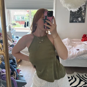 Snygg partytop  - Festligt och elegant linne i en olivgrön färg med inslag av guldskimmer. Endast använd 1 gång och är i storlek 34, men skulle passa bra på en storlek 36/38 också. 