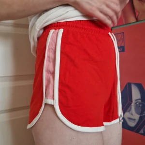 Mjukisshorts - Söta röda mjukisshorts från Monki, med rosa och vita detaljer. Aldrig använda, prislappen sitter kvar. Originalpris 100 kr.