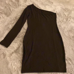 Enarmad svart klänning - Svart enarmad klänning med ribbat tyg. Aldrig använd. Ser finare ut på, skriv om ni vill se den på.