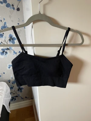 Sportbh - Svart ribbad sport-bh. Medium support. Justerbara axelband. Från aimn. 