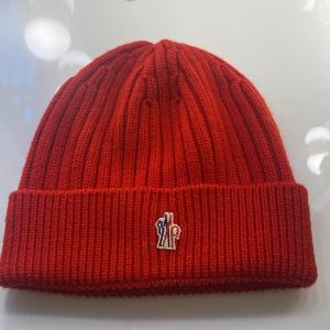 Moncler mössa - Hej! Säljer denna moncler mössan som är röd❤️har endast använt den fåtal(!!) gånger då den inte passar mig så bra. Den är självklart äkta. Unisex. Inköpt på nk nypris 1499:-  tryck gärna på köp nu❤️