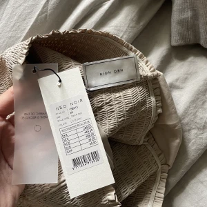 Kjol från neonoir - Beige/brun kjol från neonoir! Aldrig använd, prislapp kvar. Mycket fin kjol med fina volanger! Perfekta sommarkjolen. Ny pris 449kr