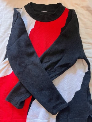Stickad tröja med mönster - Abstrakt mönster med färgerna vit, röd och svart. Finstickad tröja köpt second hand. Tyvärr är storlekslappen avklippt men skulle säga storlek m, jag är 177cm. 