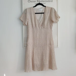 Blommig klänning  - Ej stretching material, dragkedja vid sidan.