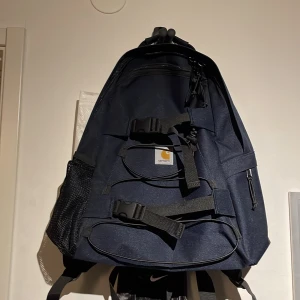CARHARTT BACKPACK - Oanvänd Carhartt ”kickflip” ryggsäck med bra plats, 1 stort fack med 2 sidofack för tex vattenflaska och 1 mindre mitt på för smågrejer. Cond 10/10 ✨