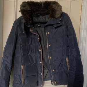 Pomperjacka med luva - Det finns en luva som går att gömma inom en dragkedja. Storleken är mindre än vad man tror. Jag har vanligtvis S/M och långa armar och den var lite kort vid handlederna. Använd men inga skador. Djur & rökfri