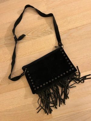 Svart väska med fransar - - En svart vintage väska med fransar och metal cirklar  - Använd med är i bra skick förutom inne facket som är trögt att stänga men inga problem att användas ändå🩷 - Pris kan diskuteras 