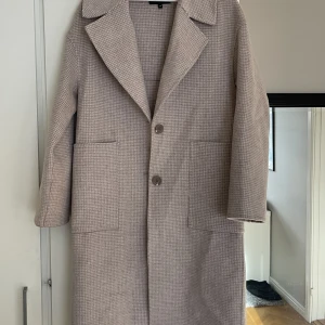 Kappa från Kappahl - En beige/rosa rutig lång kappa från Kappahl, använd fåtal gånger.