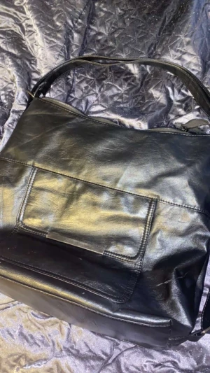 Svart väska - En svart väska som är väl använd men är i ett bra skick.  