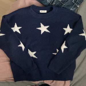 Stickad marinblå tröja med stjärnor. Den är i bra skick, lite nopprig. 