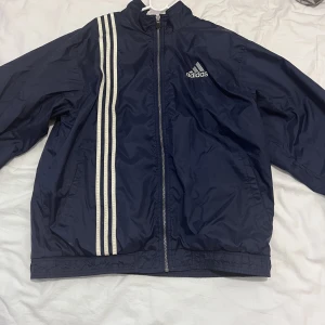 VINTAGE ADIDAS MUNKJACKA - En riktigt fin och gammal adidas munkjacka från 80/90 talet. Den har endast ett liten fel på insidan där materialet har gått sönder lite. Annars är jackan i toppskick och har en baggy feel till den. Det är storlek M. Men passar mer som en M/L på mig. 