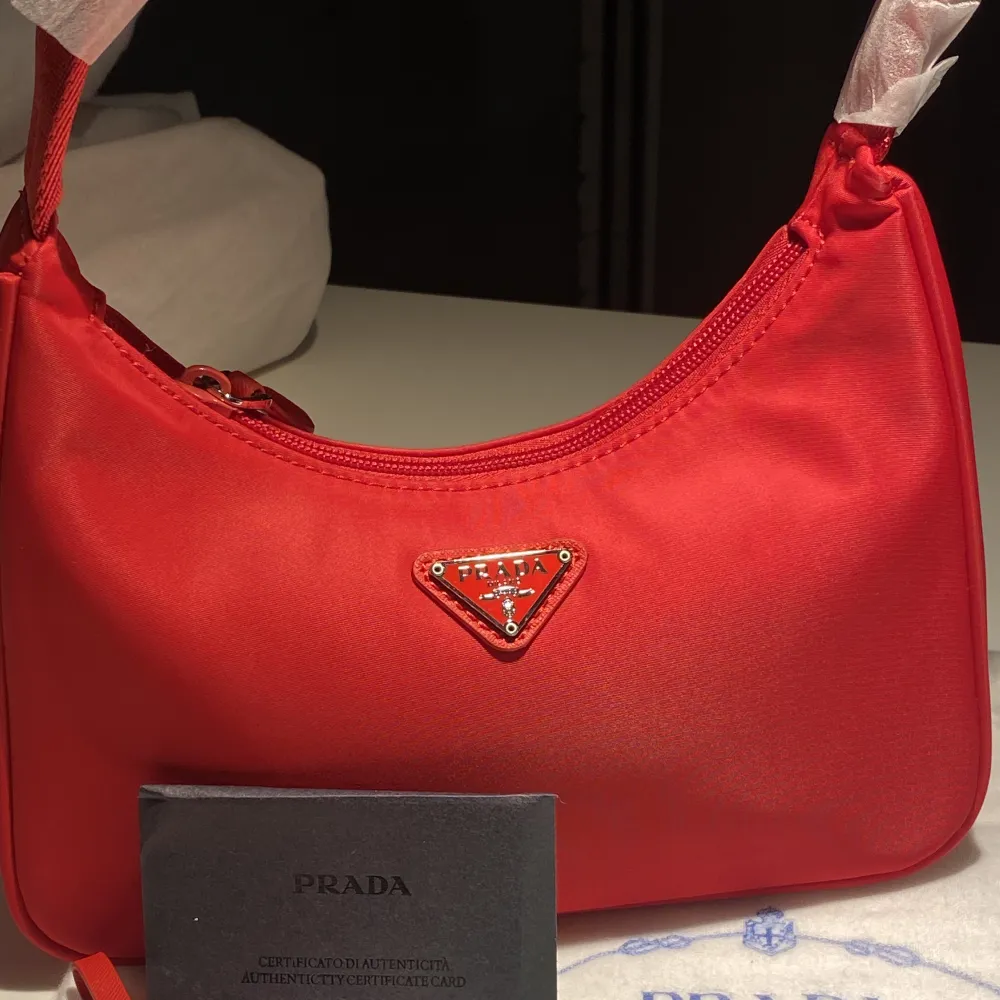 Säljer en oanvänd Prada Re-edition mini bag i röd färg. Köpt från Plick! Fraktas spärbart & försäkrat på köparens bekostnad. ❤️. Väskor.