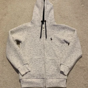 Polo Ralph Lauren Zip Hoodie  - Nästan oanvänd vit huvtröja med dragkedja från Polo Ralph Lauren. Väldigt bra skick och storlek Medium (M). Originalpris: 1500 kr.
