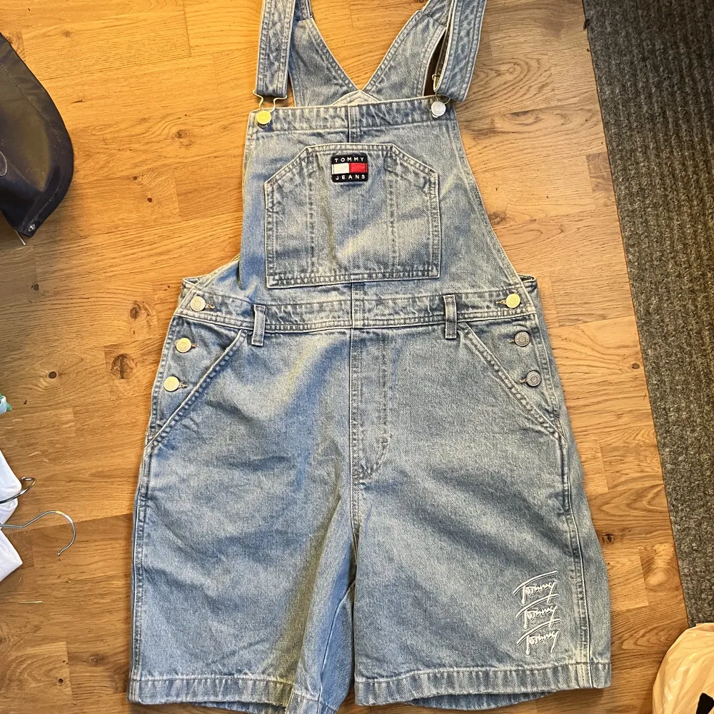 Tommy Hilfiger hängselshorts i stl M säljes. Använda en gång. Avslappnad stil, oerhört sköna. Snygg tvätt. Lagom sliten look längst ned vid byxlinningen. . Shorts.