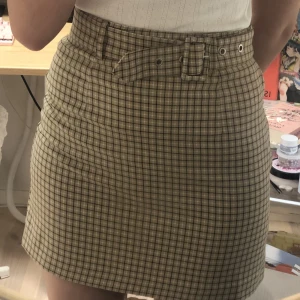 rutig kjol - gul/beige kjol med rutmönster. märke okänt. sitter tight på mig som är 36 och är ganska hög i midjan. bältet går att ta ut.
