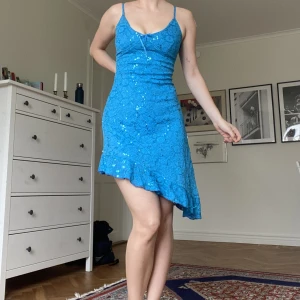 Unik djerf blå klänning med volanger - Unik klänning med volanger och lätt asymmetrisk nedtill. Diskret glittertråd i tyget. Superfin! Passar en S/M.🦋