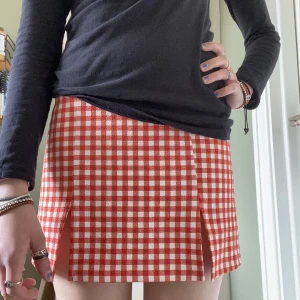 Vit och röd rutig kjol - En vit och rödrutig mini kjol. Den är högmidjad och har en dragkedja på baksidan av den. 