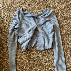 Stickad kofta  - Stickad blå kofta. Tunn av sig. Går att använda som topp bara. Alla knappar för att knäppa 