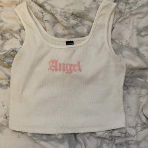 Vit magtröja med rosa text som det står ”angel” på. Fint använt skick Lite genomskinlig Köpt på shein.