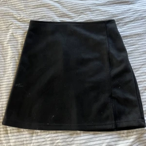 Svart kjol - Jättefin och skön svart kjol i sammetstyg. Har dragkedja och slits. Använd ett fåtal gånger & har inga skador eller liknande:)