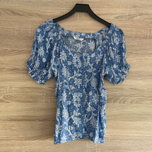 Blus - Blommig blus med knappar och en fin skurning vid halsen.