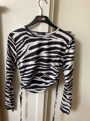 Zebra mönstrad topp - Oanvänd topp med knytning i sidorna. Strl L men passar mig som har S/M då man kan dra ihop den på sidorna.