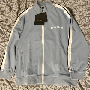 Palm angels track tröja  - En snygg ljusblå tröja med dragkedja med märke Palm angels. Storlek M inte använd