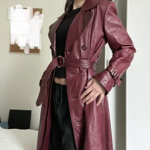 Vintage skinnkappa - Så snygg vinröd. Äkta skinn. Går till mitten på vaderna på mig, jag är 164 cm och bär XS/S. Står ingen storlek i jackan.