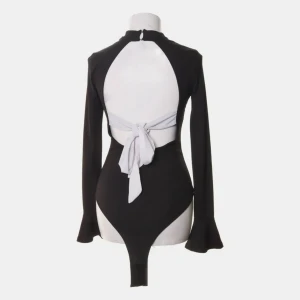 Svart body med öppen rygg - En superfin svart body med öppen rygg och vita band som man kan knyta till en rosett. Köpt via Sellpy men den är från Gina Tricot. Säljer pga att den inte kommer till användning!