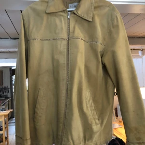 Skinnjacka - Beige skinnjacka i western stil.  Strl 50. Jag är 180 lång, om det är till någon hjälp.  Stängs med dragkejda och med fickor på bägge sidor.  Sparsamt använd och i gott skick, dock med en antal fläckar. 