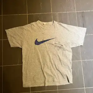 Vintage Nike t shirt. Färgen är grå, den har ett stort hål som syns på bilden. Storlek L
