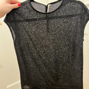 Glittrig stickad T-shirt - Guld/svart glittrig stickad topp Lätt genomskinlig. Nyskick!!