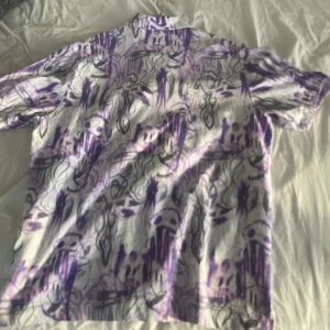 Baggy kortärmad skjorta - Bekväm och stor vit skjorta med lila mönster på. Bra kvalitet, inga fläckar och inte så använd.