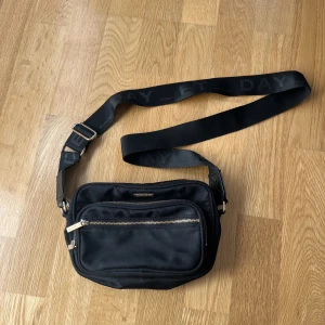 Axelremsväska  - Säljer nu min axelremsväska då den inte kommer till användning längre, är i ett bra skick med ett stort fack som innehåller 2 mindre fack, väskan har även två fack på utsidan. 