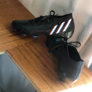 Adidas predator - Hej! Säljer nu dessa  adidas Predator Edge 2 i färgen Shadowportal (Svart/Vit/Röd) Nypris ligger på ca 1500.  Dem är andvända i ca 2 månader och skicket är 8/10. Kan mötas upp i sthlm och kan frakta Vid fler bilder eller frågor tveka inte att fråga👍