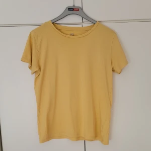 Gul t-shirt - Gul T-shirt från Lager 157 i storlek M. 100% bomull. Den är ganska lång men går att vika in, som på bilden. 52 cm lång från hals till midjan. 