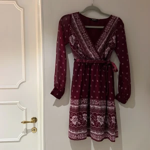 Fin långärmad klänning - Fin långärmad klänning från Asos- perfekt julklänning. Röd med  knytband, samt dragkedja i sidan. Strl UK 6