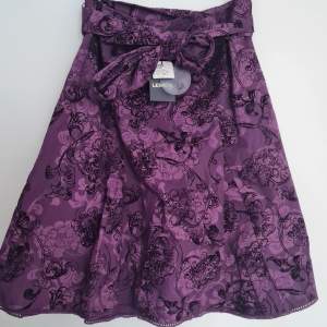 Lila kjol med blommigt mönster. Aldrig använd - prislapp sitter kvar. Nypris: 795kr Säjs för 350 exklusive frakt