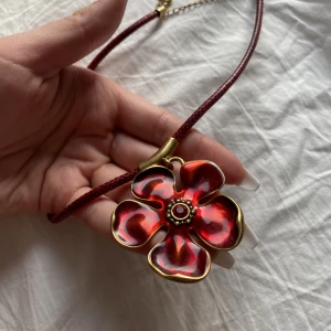 Halsband blomma - Säljer en riktig statement piece som levlar upp ens outfit! Ett jättefint rött halsband med en berlock i form av en stor blomma! 🌤️🌸