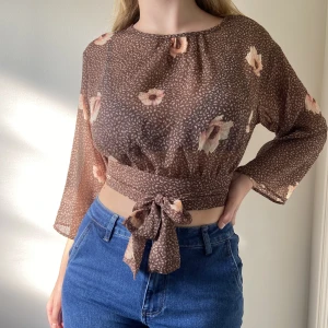 Blommig blus med knytning - En söt brun blommig blus med knytning som passar Xs-M!