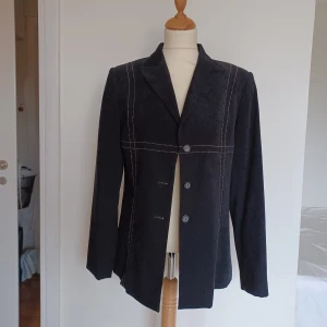 Svart kavaj - Svart kavaj med vit contrast stitch. Lite faux-mocka liknande tyg. Toppenskick.