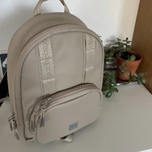 Duche bag  - Beige ryggsäck från duche bag. Väldigt sparsamtanvänd så i fint skick! Smidig och gullig väska som man också lätt kan koppla ihop med andra väskor från märket. 