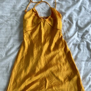 Orange kort silkesklänning - Orange kort silkesklänning med korsade band och öppen rygg, helt oanvänd!