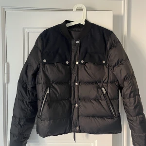 Lätt/tunn dunjacka - Tunnare dunjacka från J.Lindeberg, använd fåtal gånger. Blekare svart färg och mörkblåa pads på axlarna 