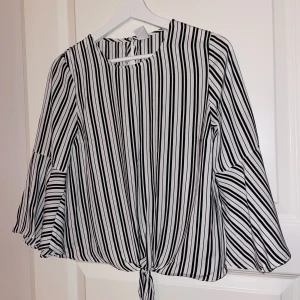 Svart vit randig blus med volanger - Super gullig blus med lite volanger vid änden av ärmarna och knytning vid ”magen” då den är lite croppad. 