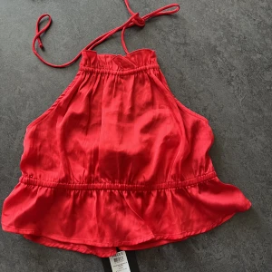 Topp - Söt kortare topp. Volanger, öppen i ryggen med knyten i nacken. Glansigare material. Märke: Pieces Storlek: 34/XS Färg: Röd   ALDRIG ANVÄND, prislapp kvar.  Nypris: 229kr