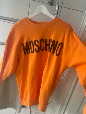 Moschino sweatshirt orange  - Orange sweatshirt från Moschino.  Skick 10/10 endast testad hemma, sedan hängt i garderob 