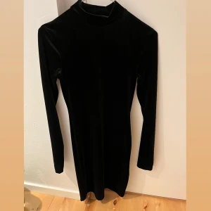 Klänning  - Svart klänning med lite högre krage, endast använd 1 gång på nyår. Väldigt mjukt material 